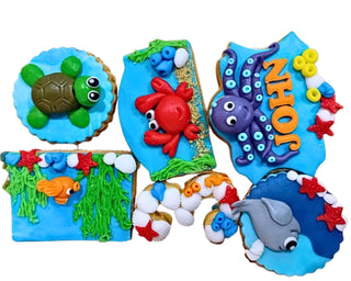 Biscotti decorati artigianali a tema animali marini con tartaruga, polpo, pesci e delfino in pasta di zucchero, ideali per feste e compleanni a tema mare.